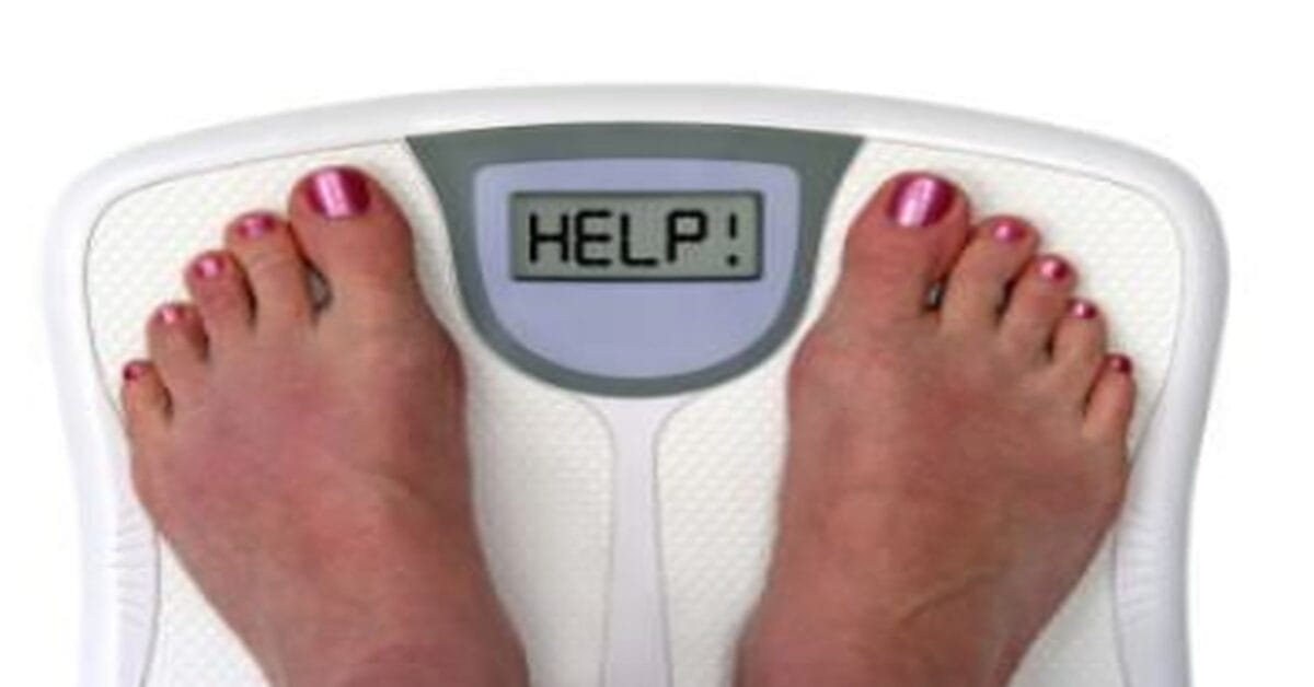Feet standing on a bathroom scale displaying 'HELP!' symbolizing frustration with weight loss struggles